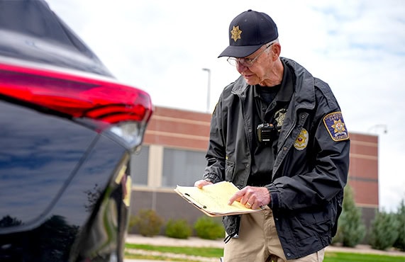 Officer from Douglas County Sheriff's Office writing a report beside a vehicle.